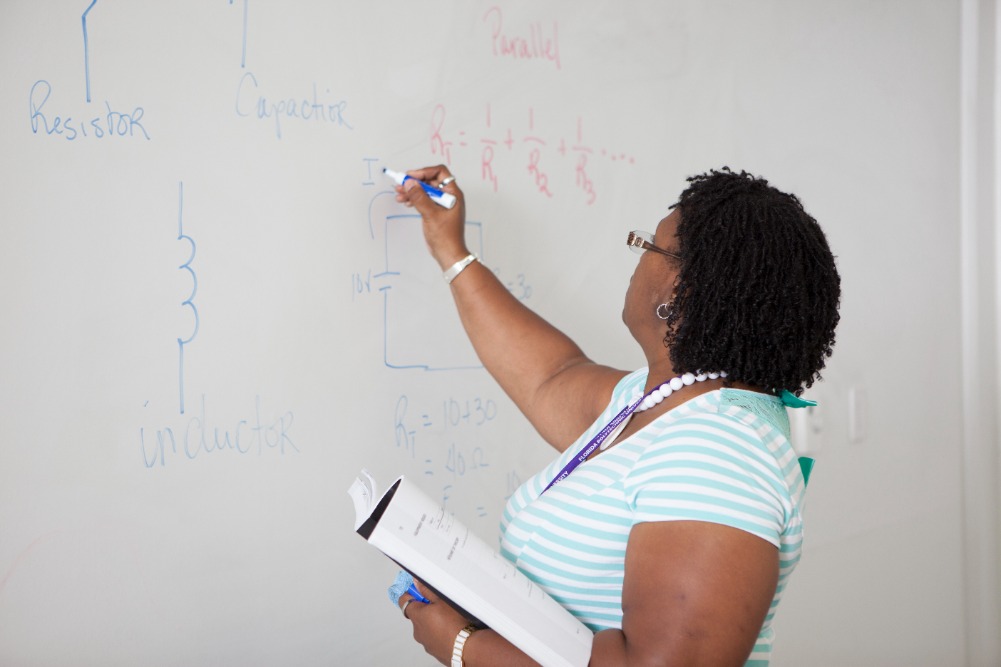 Female faculty member writing on the white board.