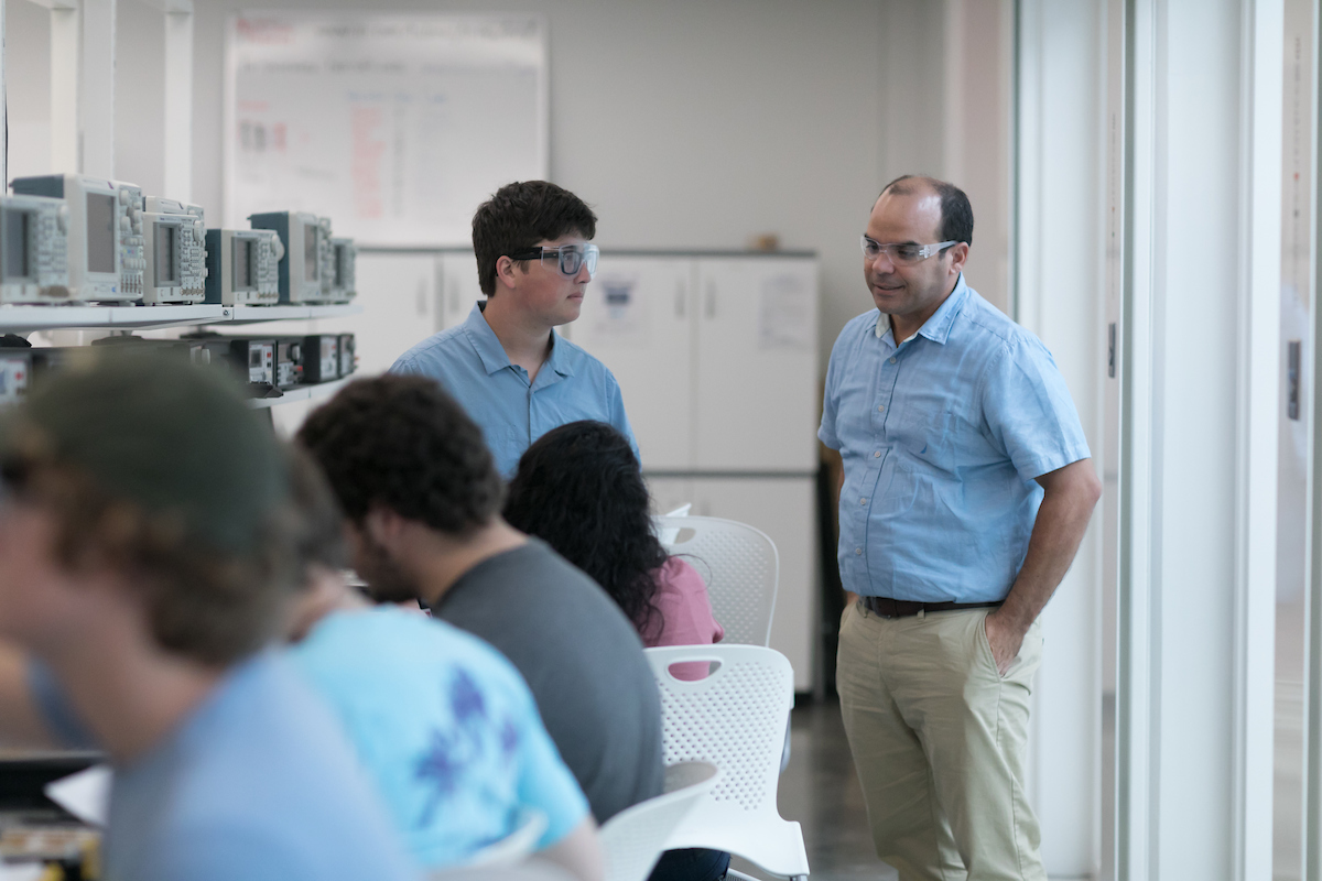 Students working with a professor in an electrical engineering class.